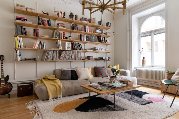 уютен хол с етажерка за книги и голям диван с възглавници в скандинавския стил